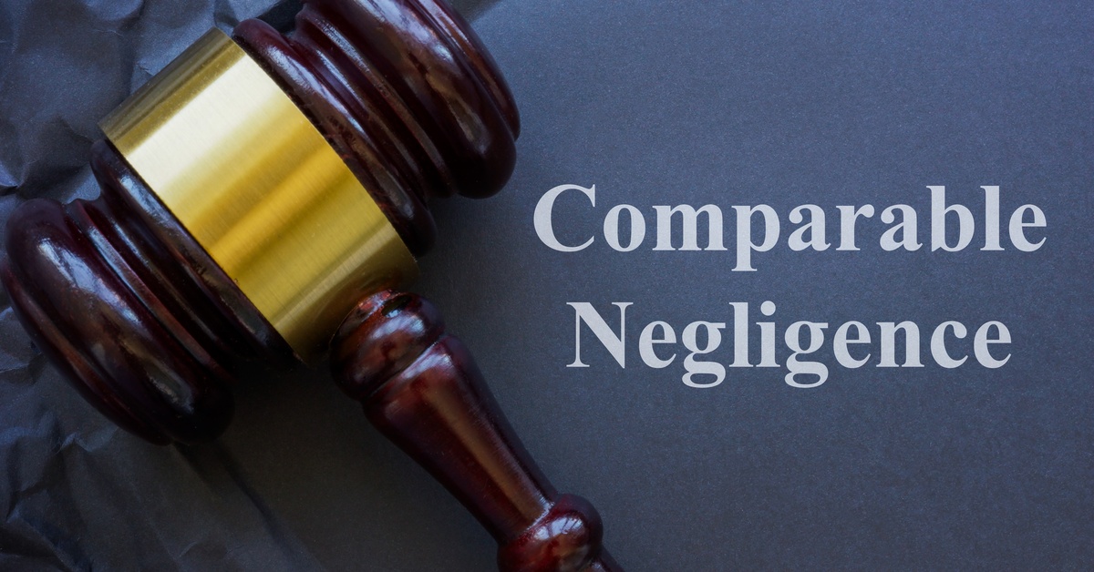 A dark wooden gavel with a gold stripe on crumpled dark-blue paper featuring the words "Comparable Negligence" in white text.